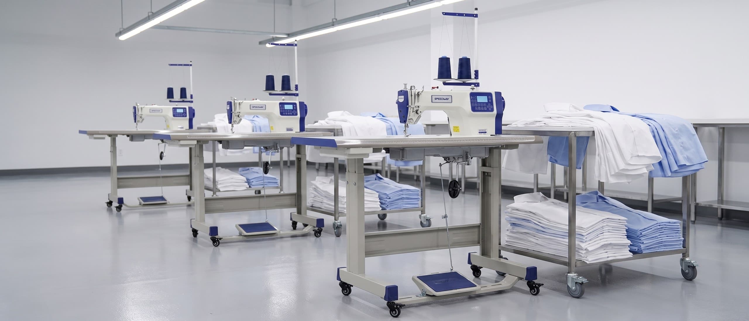 Modern apparel production line — receding row of SPEEDWAY AI4 direct-drive lockstitch machines on their tables with folded shirting panels