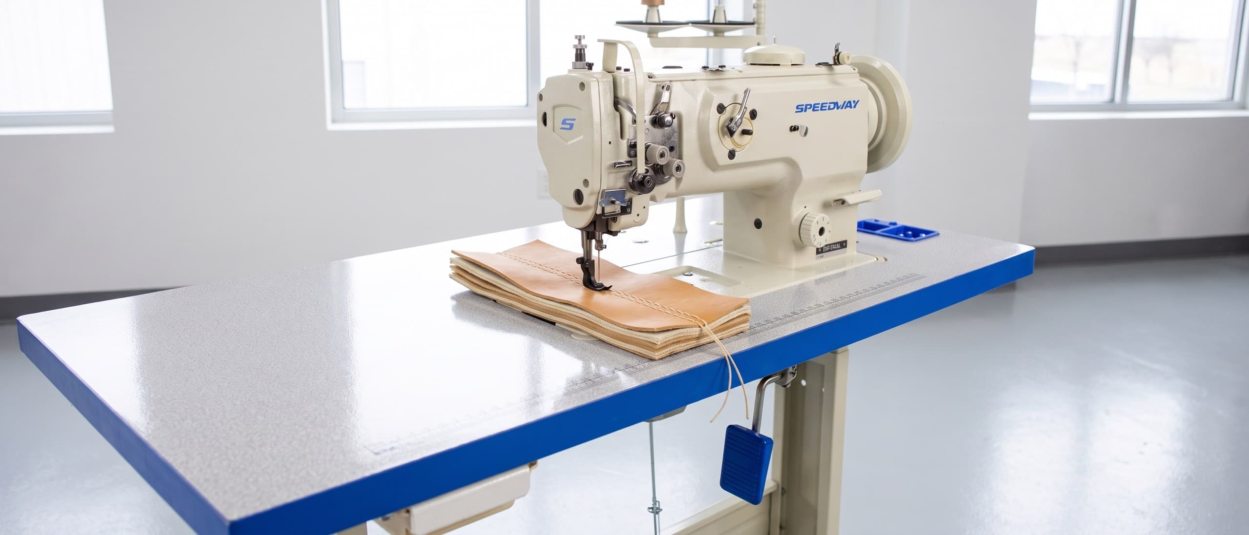 SPEEDWAY SW-1510L heavy-duty walking-foot machine sewing through a thick stack of leather and canvas layers on its Speedway table